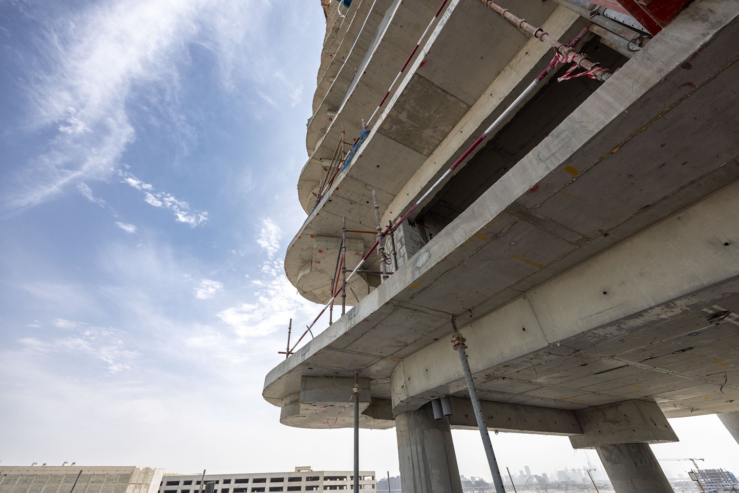 Beach Walk Residence Construction site view featuring concrete structures, scaffolding, and a clear blue sky.